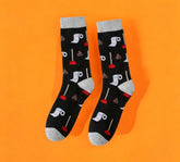 Funny Toilet Paper and Plunger Pattern Socks with a black base and colorful toilet paper roll and plunger design, laid flat on an orange and peach background.