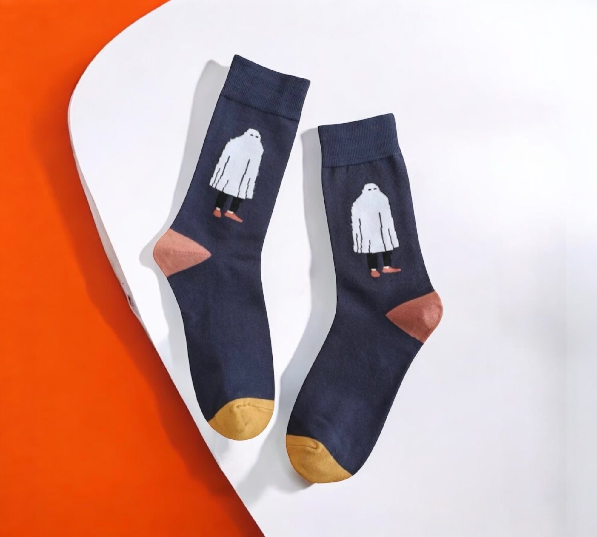 Stylish Ghostly Chic Halloween Socks featuring a white ghost design, mustard toes, and terracotta heels, laid flat on a white and orange background.