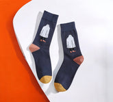 Stylish Ghostly Chic Halloween Socks featuring a white ghost design, mustard toes, and terracotta heels, laid flat on a white and orange background.