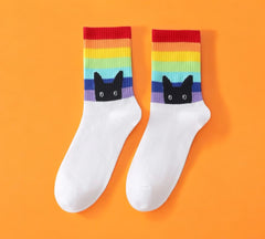 Peeking Cat Rainbow Pride Socks - White color with rainbow stripes and black cat design, laid flat on orange background.