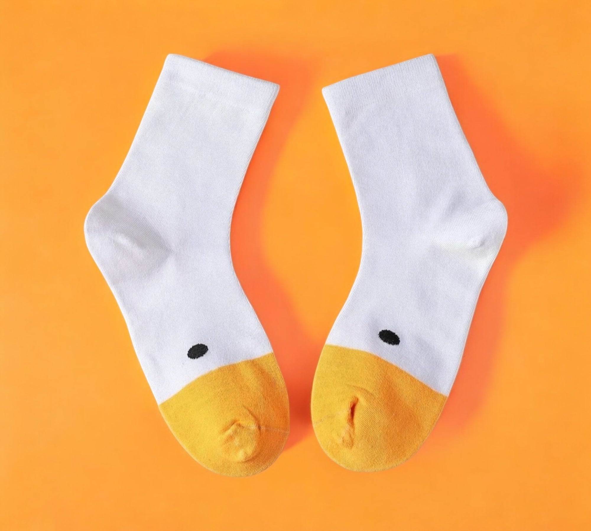 Adorable Silly Goose socks laid flat on an orange background.