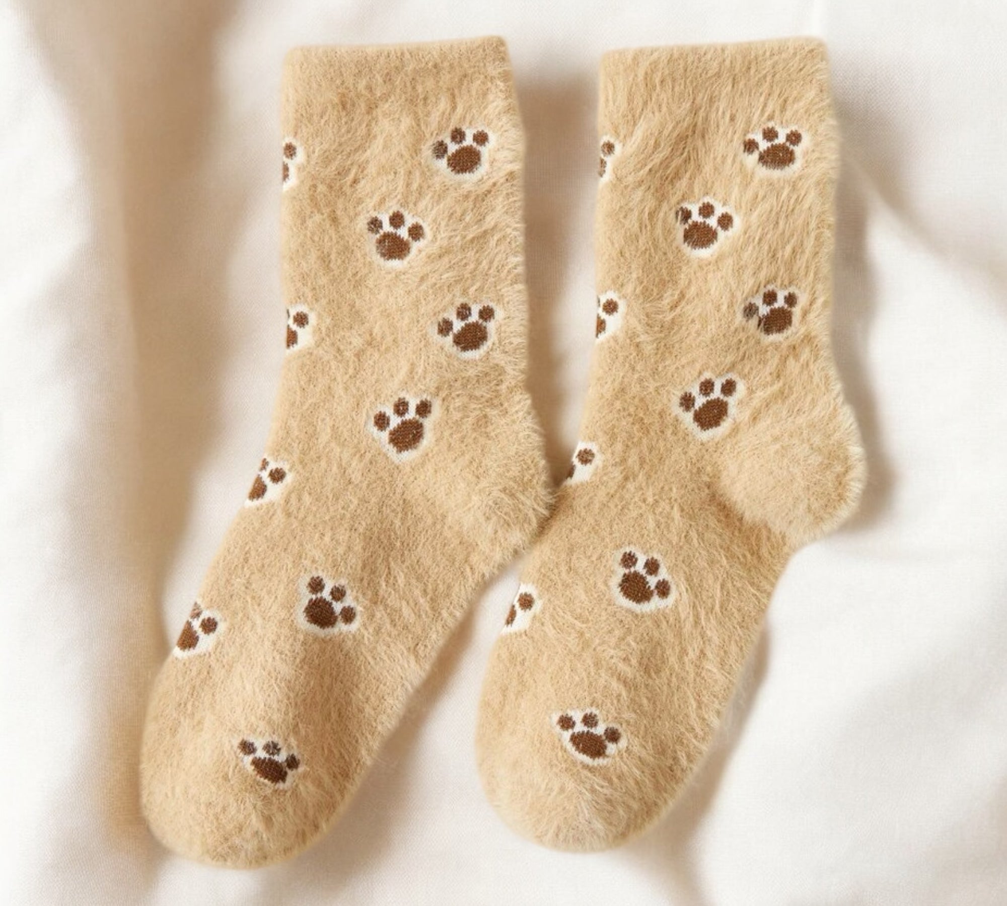 Cozy fuzzy socks in beige with adorable brown paw print pattern, perfect for pet lovers and winter comfort.