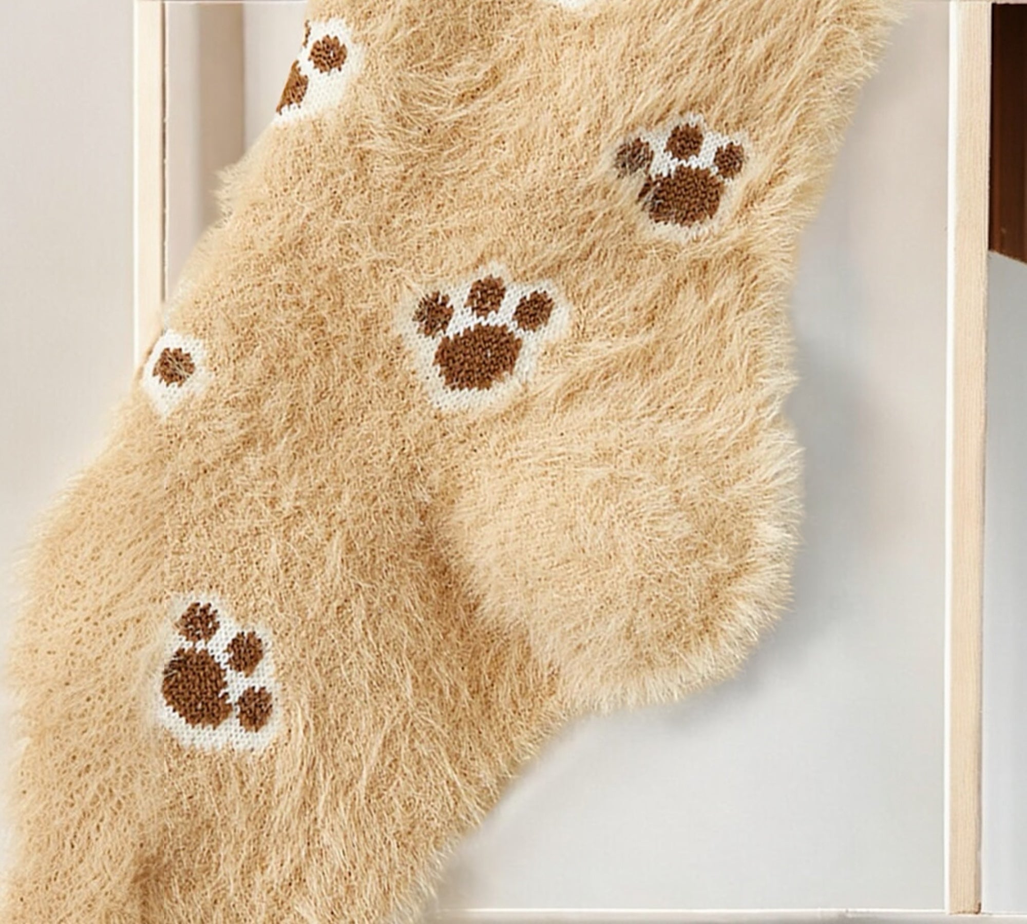 Cozy paw print socks laid on white bedding, highlighting their soft, fuzzy texture for ultimate comfort.