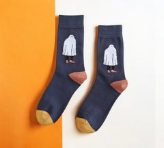 Quirky Halloween socks with a ghost motif, crafted in a breathable cotton blend, displayed on a split white and orange backdrop.