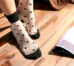 Romantic sheer socks with black hearts, perfect for gifting or Valentine's Day, shown with stylish and playful details on a wooden background.