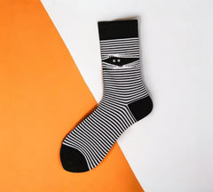 Close-up of a single Halloween Mummy Sock showcasing black-and-white stripes and a quirky mummy detail on an orange and white background.