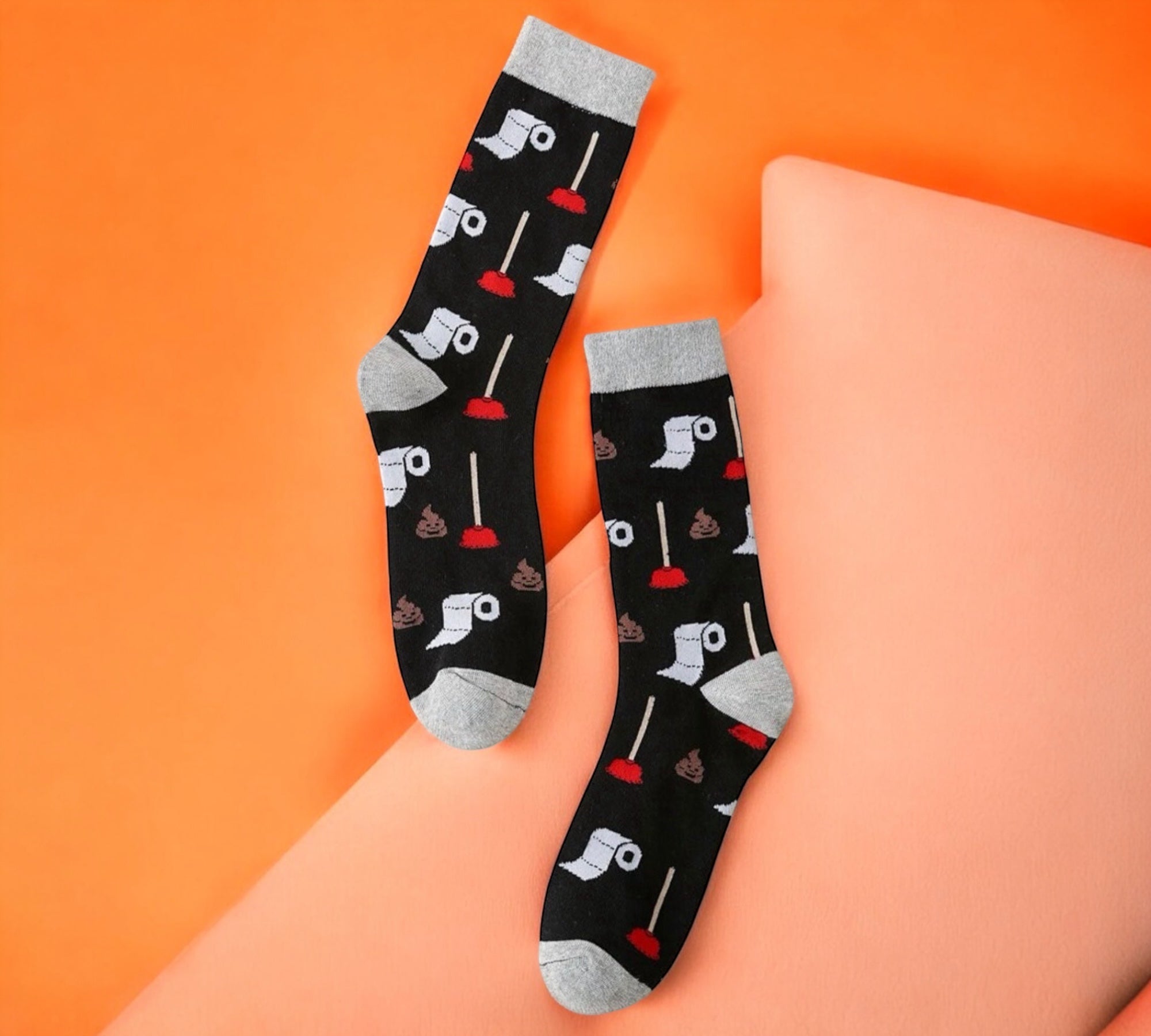 Cheeky and hilarious Funny Toilet Paper and Plunger Pattern Socks featuring poop emoji and plunger details, displayed on a vibrant orange backdrop.